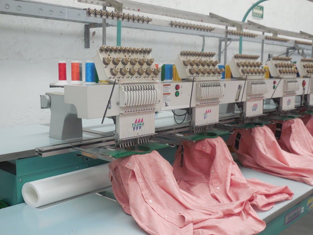 Cabezales de una bordadora multicabezal Tajima bordando camisas en BV Uniformes.